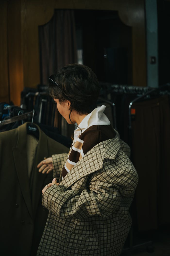 Individual browsing jackets in a cozy thrift store setting.