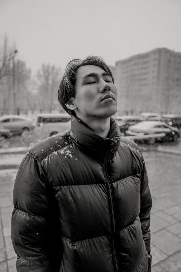 Young person with eyes closed, standing in snow, Ulaanbaatar, Mongolia.